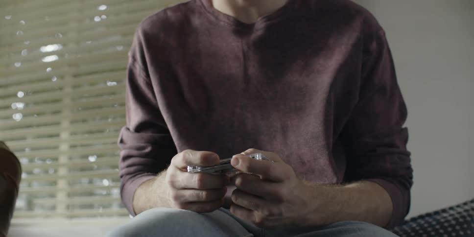 Man sits as he holds a cassette tape in his hands
