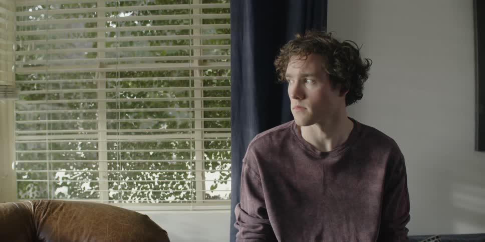 A man sitting in a room looks up and to the side