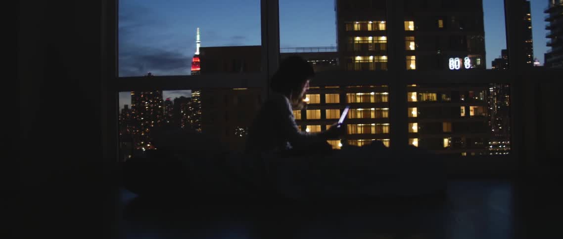 Person beside large window looks at an electronic device