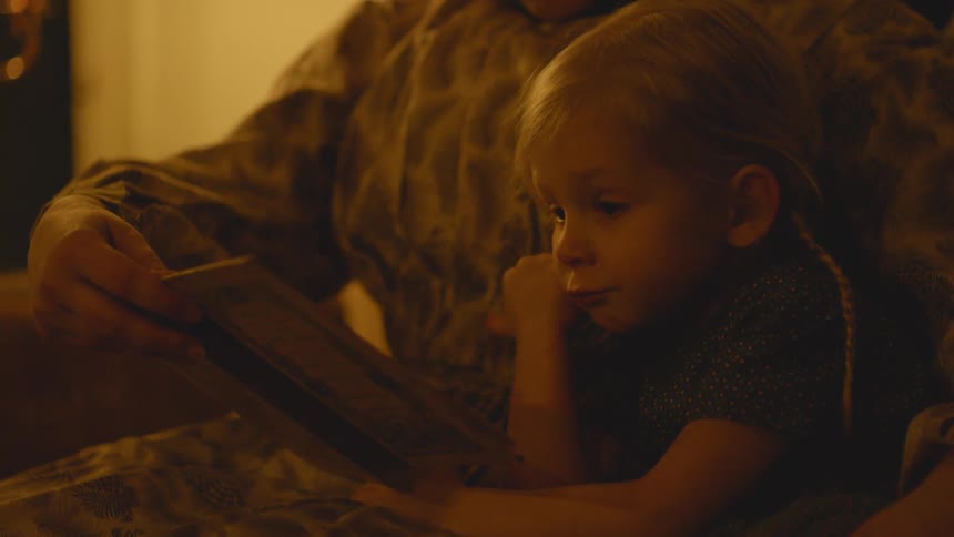 A woman reads a book to a young child