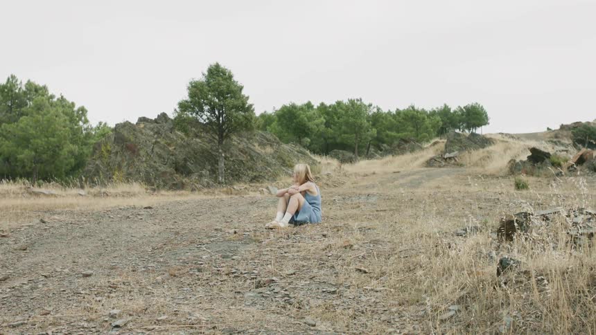 Woman sits outside in the middle of a grassy field