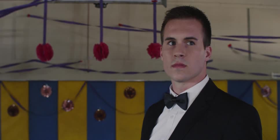 A man in a tuxedo walks in the auditorium