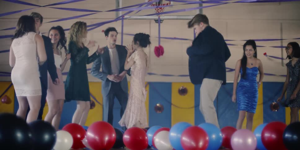 Teenagers dance on balloon covered gym floor