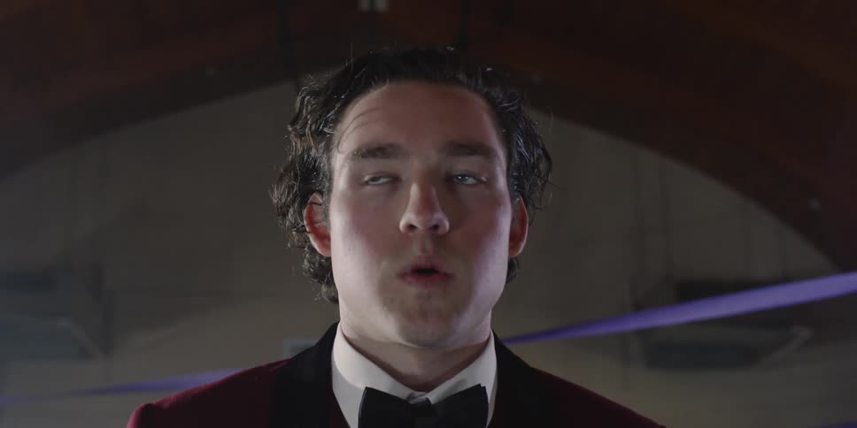 Man in red suit looks around and tries to catch his breath