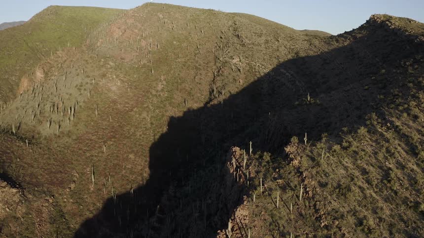 Sun shines over grassy hills casting a shadow