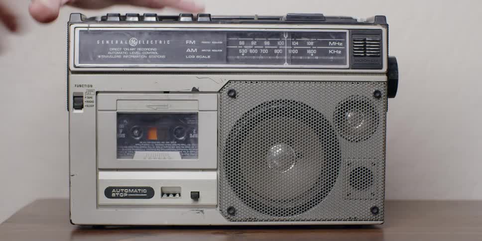 A man puts a cassette into a player and turns it on