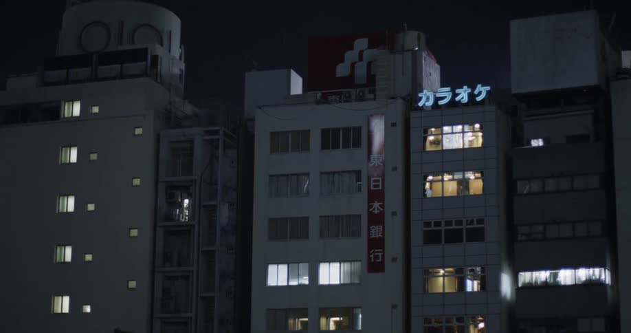 A sign flickers atop a building at night