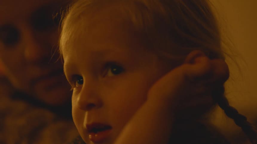 Woman cuddles a child in dim light