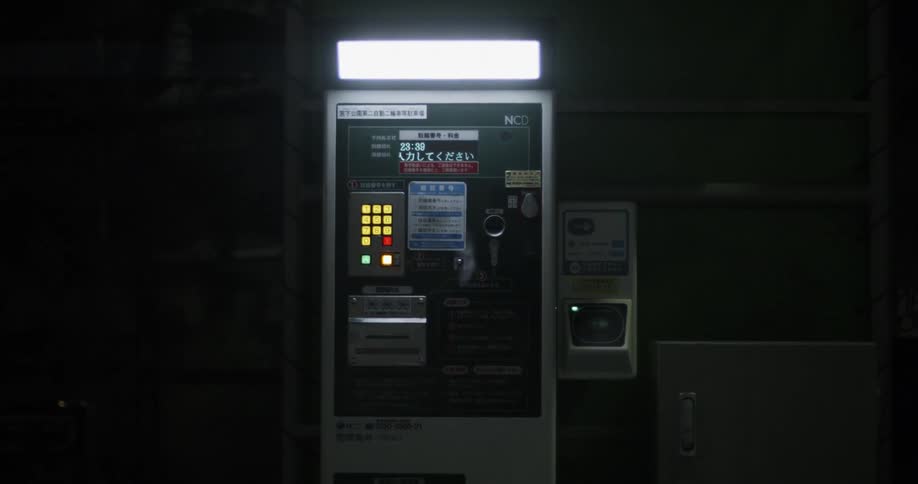 A vending machine is operating in a station in asia at night