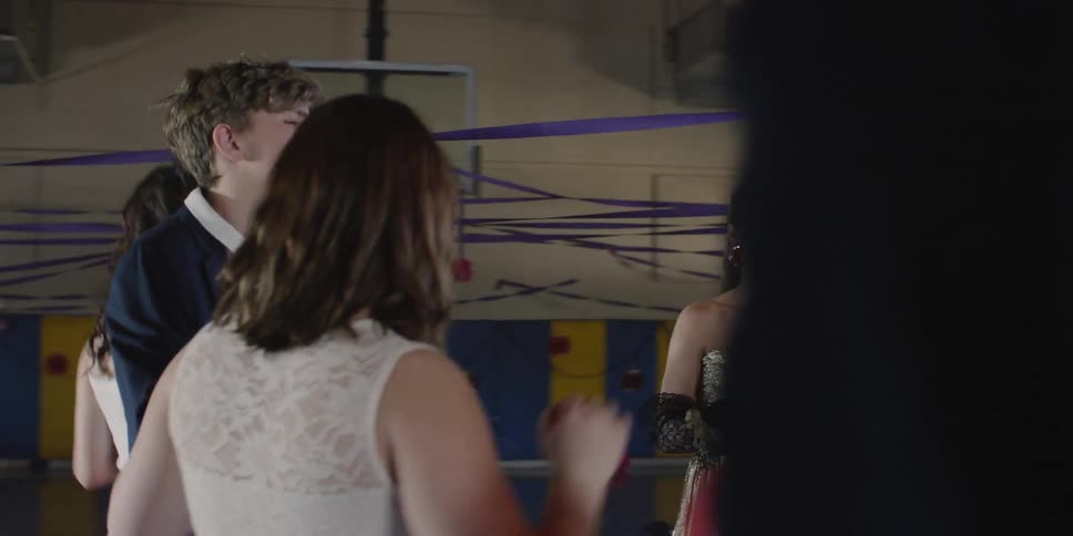 Teenagers dance in a gym hitting balloons in the air