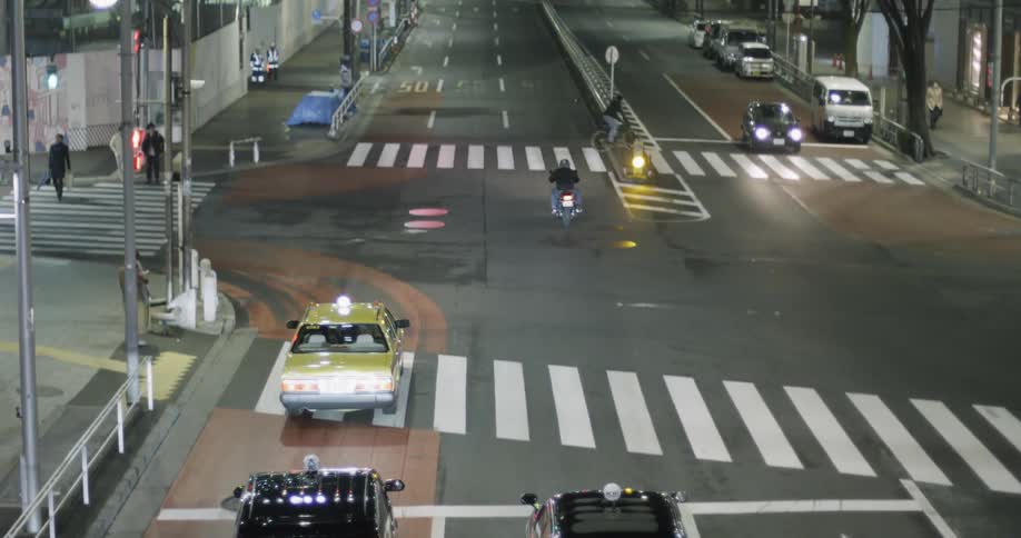 Several vehicles drive down a busy city street at night