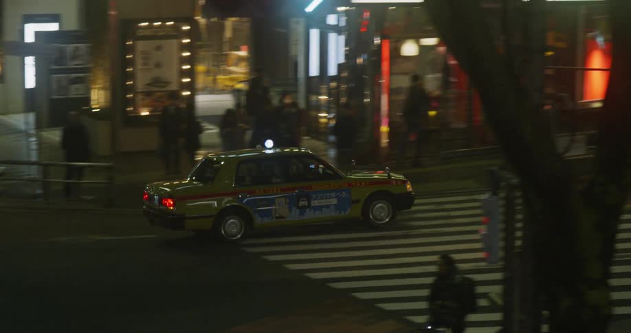 Taxi drives through a busy city street at night