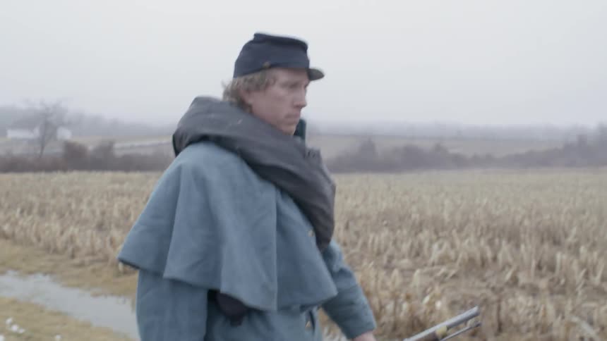 Man carrying a gun in an empty field