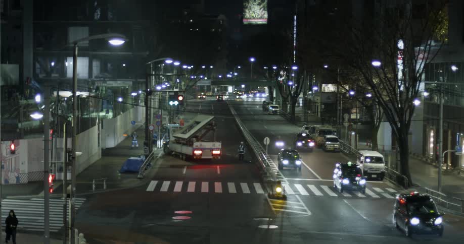 Vehicles travel down a city road at night