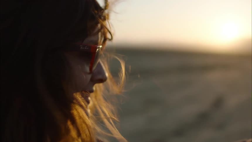 A woman stands on the beach and takes a selfie