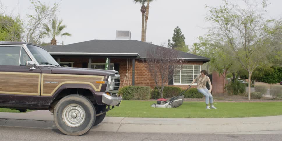 Man dances while pushing a lawnmower in the front yard
