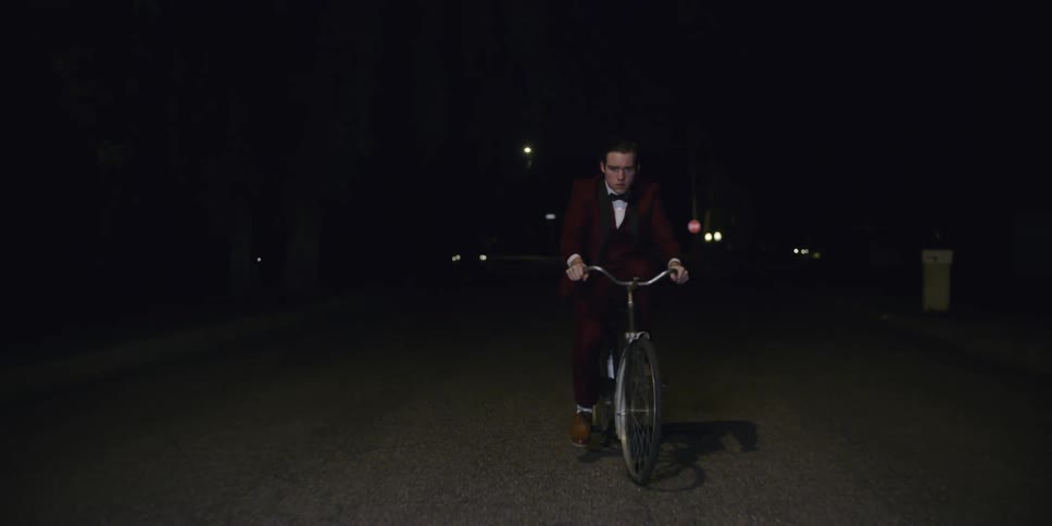 Man wearing a suit rides a bike at night