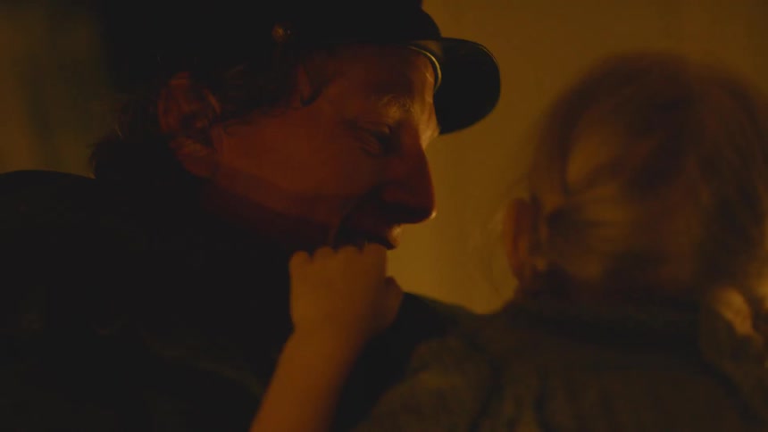 A man smiles as he rocks his child in his arms