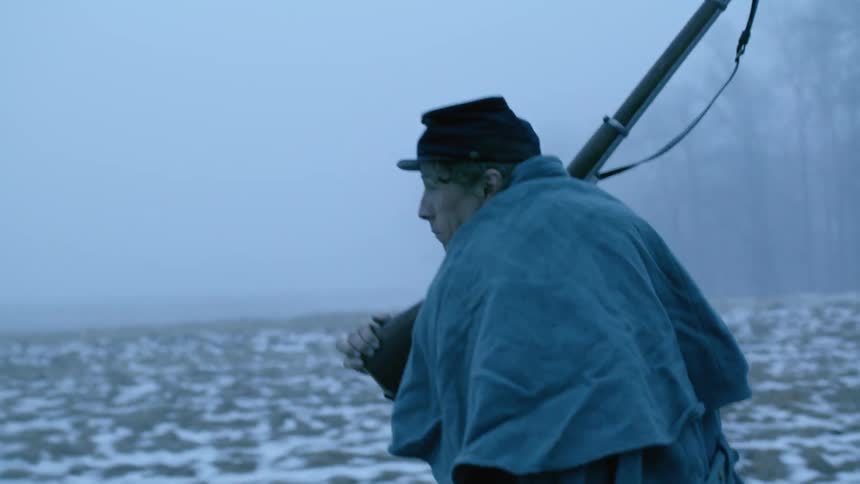 The man is carrying his rifle on a foggy day