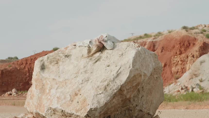 Woman lays over the top of a large rock