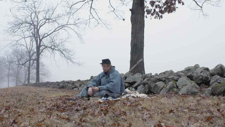 Soldier sits in a field on a cloudy day