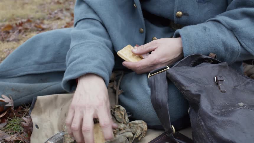 Man takes food out of a dirty pack and lays it on a ragged cloth