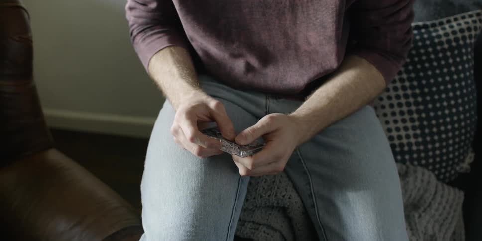 The man is tapping a cassette tape in his hands