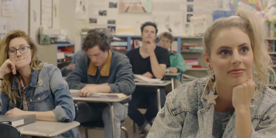 People in the classroom are seated and flipping through books