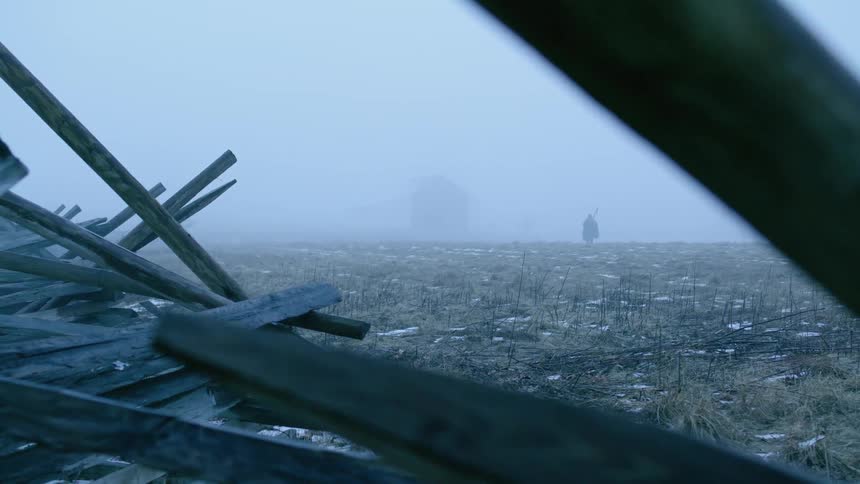 Person walks across a field on a foggy day