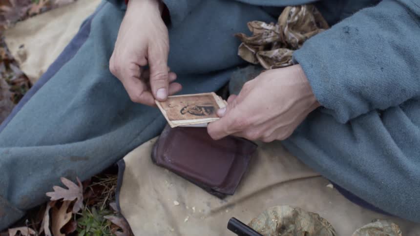 Man sits outside holding cards and puts them down
