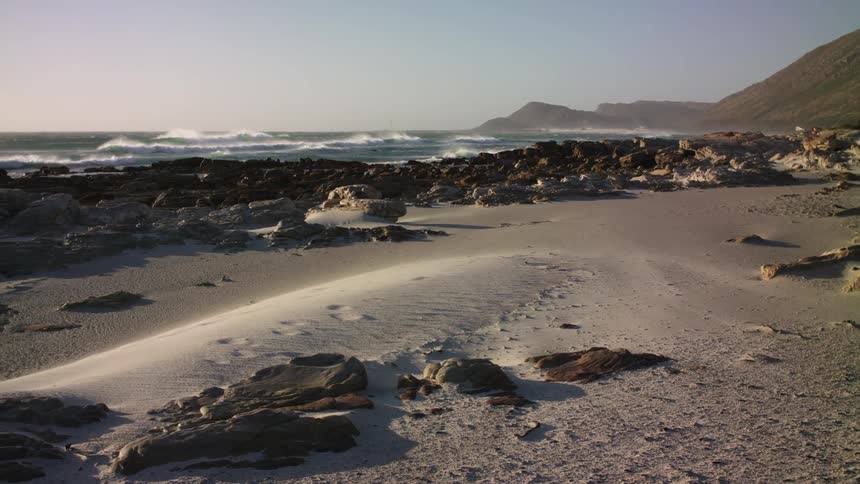 The waves crash against the rocky shore
