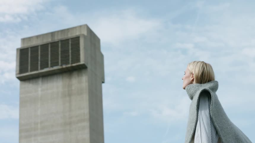 Woman stands outside next to a large concrete structure