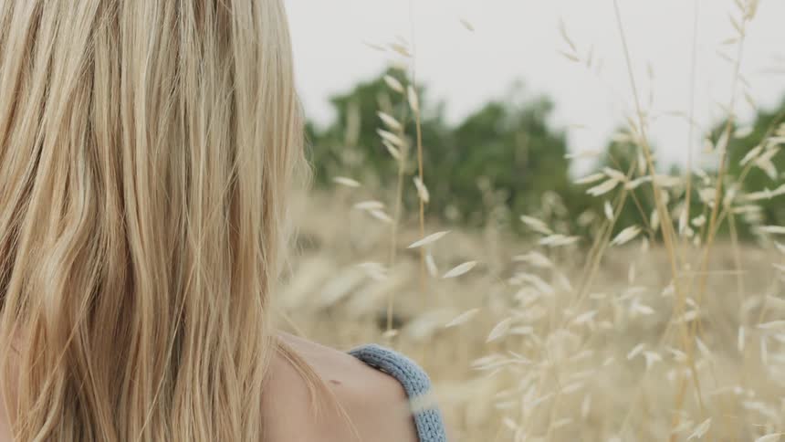 Woman stands outside in a field of tall weeds