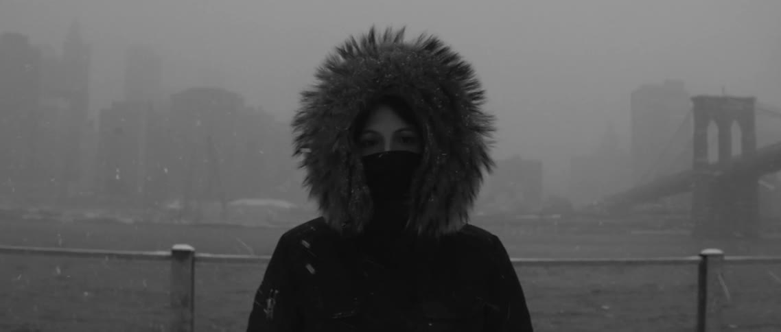 Snow swirling around a woman in a heavy coat