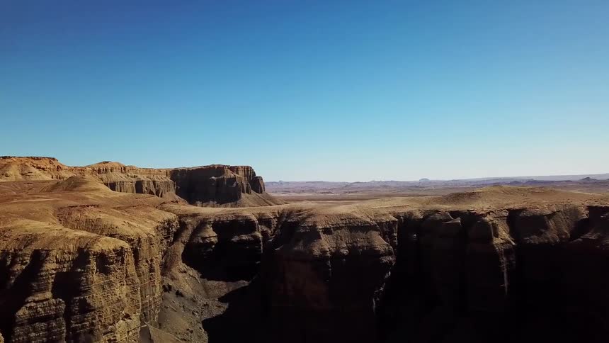 Shadows are clinging to the sides of cliffs in a desert landscape during the day