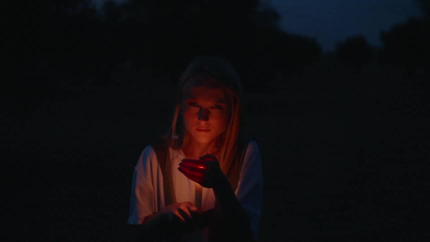 Woman's face illuminated by firelight at night