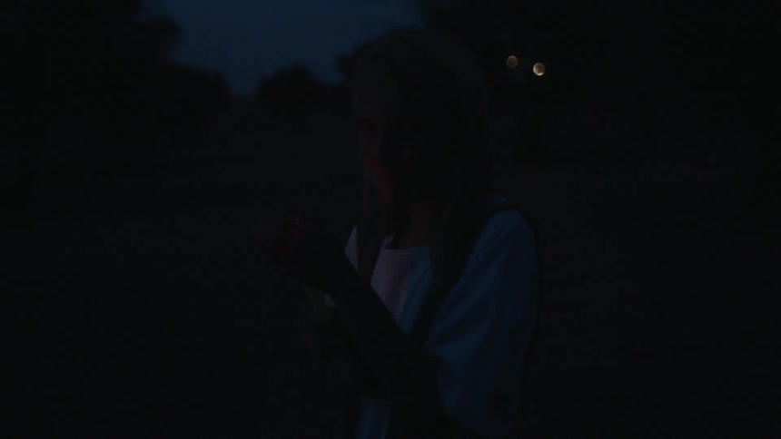Woman covers flame with her hand outside at night