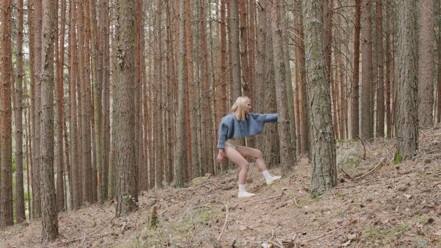 A young woman stands still in the woods