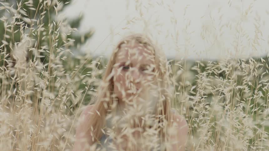The woman is sitting behind the tall grass