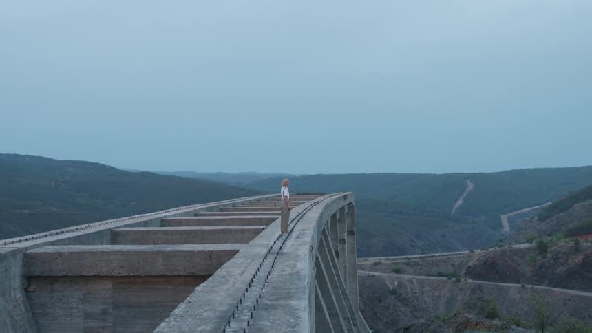 A woman stands atop a bridge