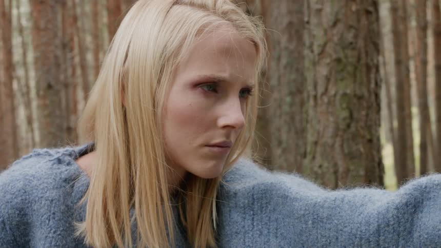A woman stands alone in the woods