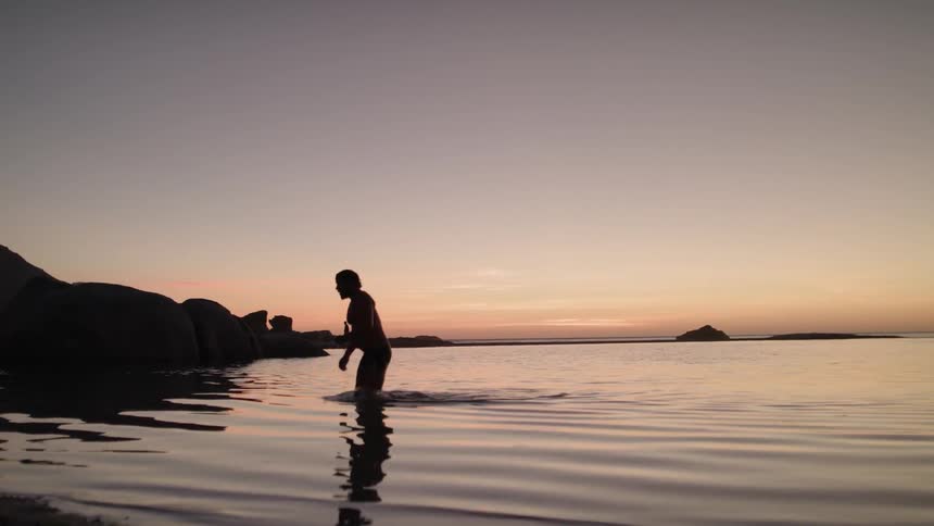 Person walks out of the ocean and sunset