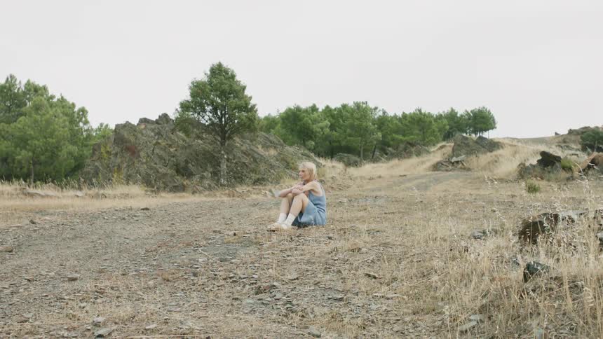 Woman sits in a grassy field on a sunny day