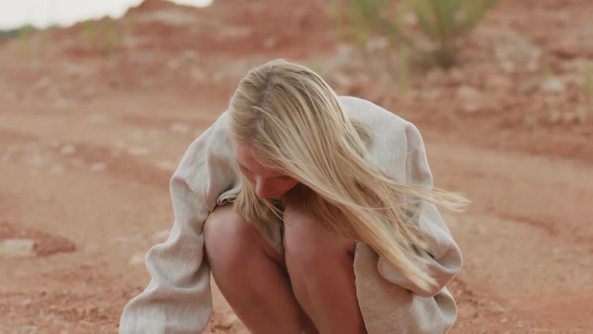 Woman kneels outside in dirt