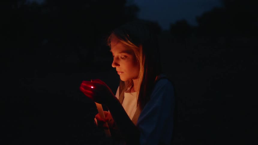 A woman lights a candle in the dark