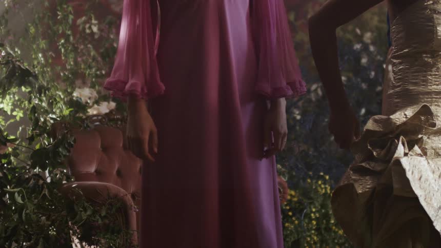 Women in long dresses stand on a set