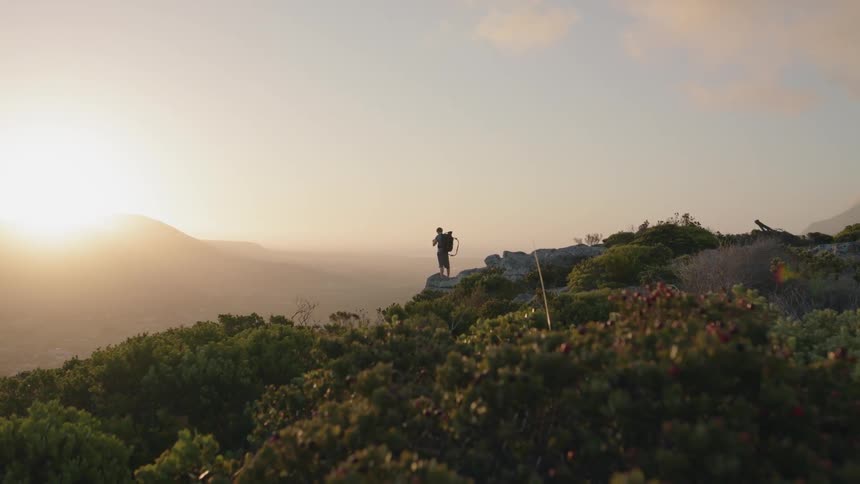 Person stands on a grassy hilltop at sunrise