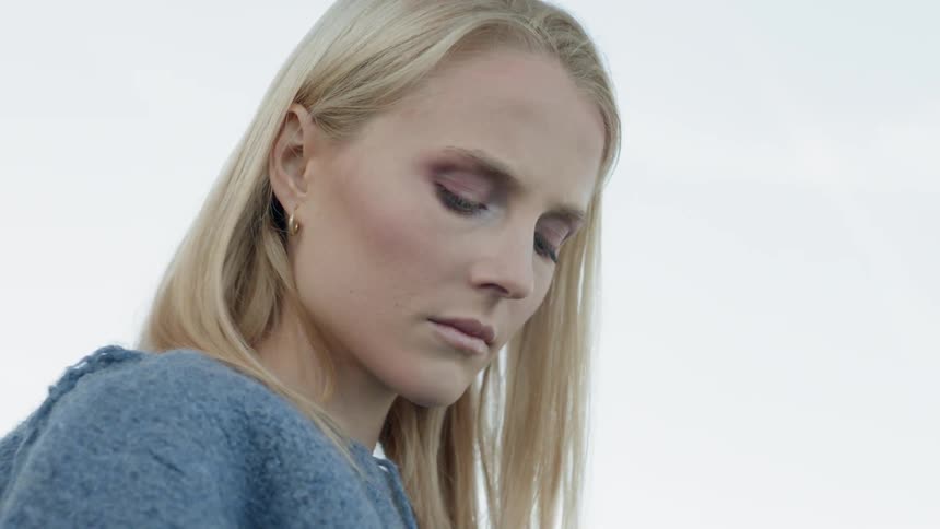 A woman looks to the side then down