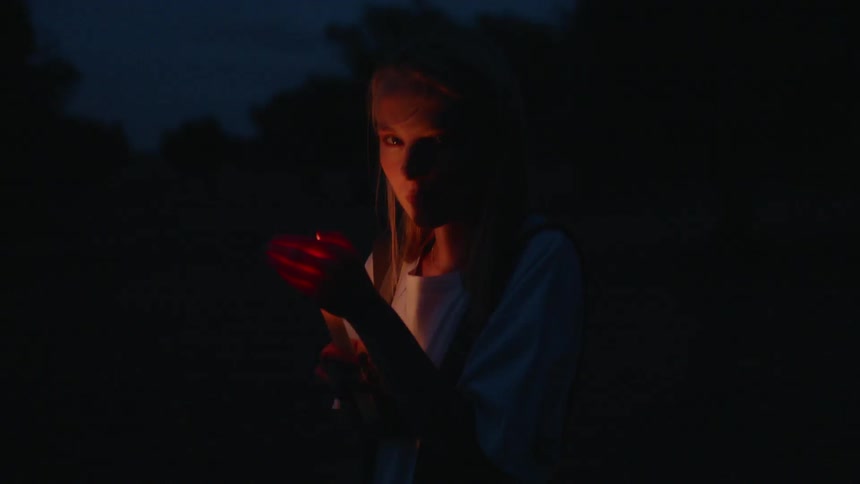A woman is covering a candle at night