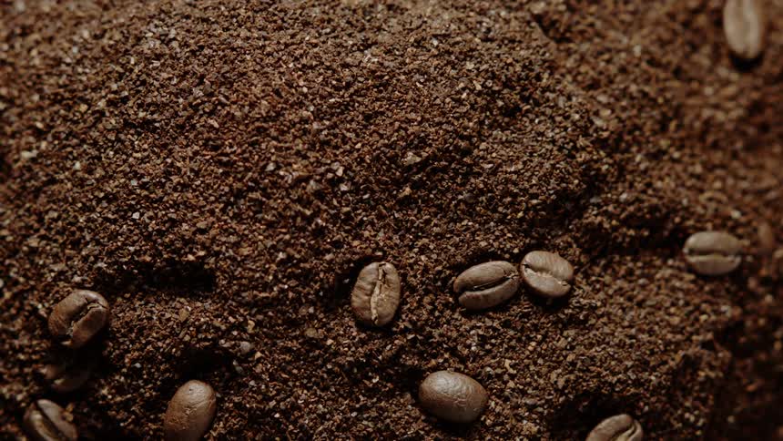 Coffee beans are falling onto pile of coffee grounds